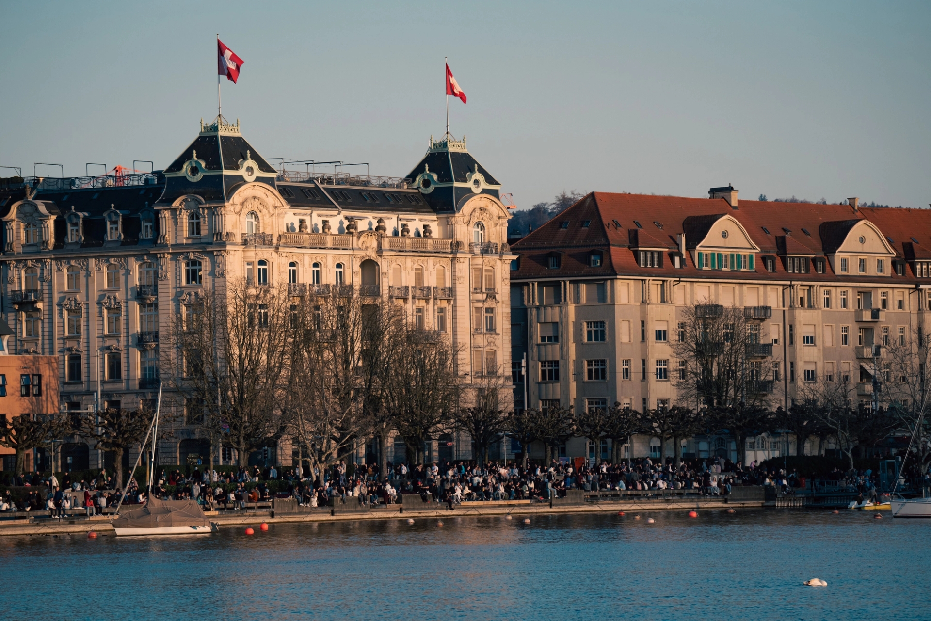 A bustling day by the Zurich waterfront with historic architecture and Swiss flags