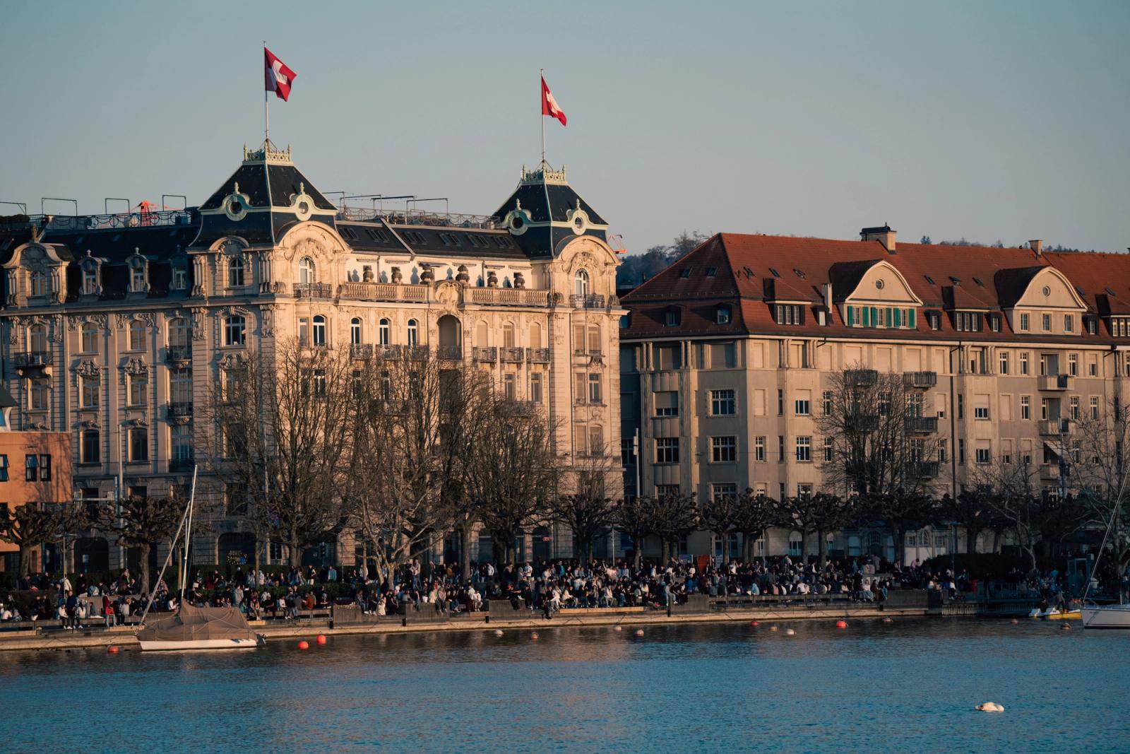 A bustling day by the Zurich waterfront with historic architecture and Swiss flags