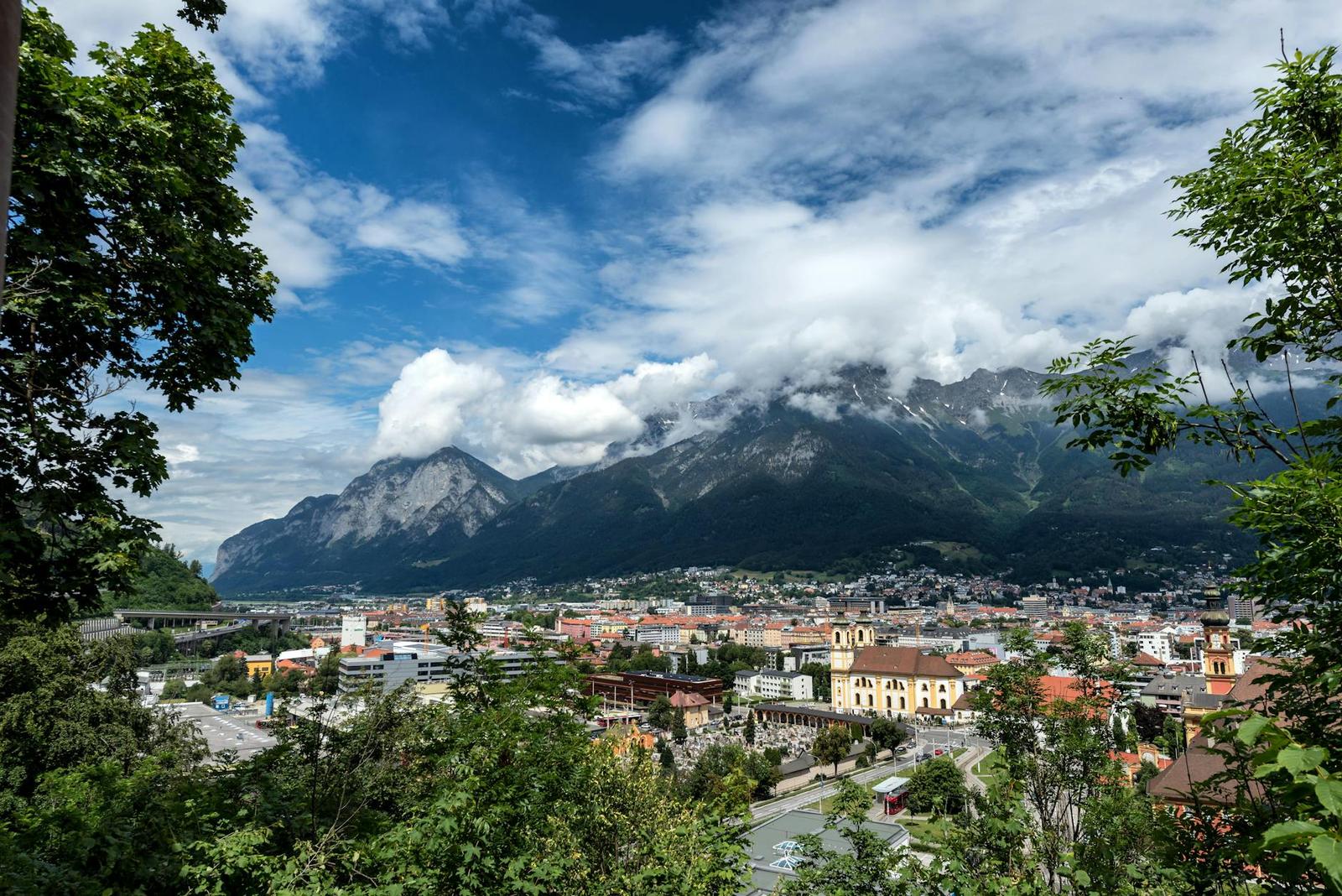 A town of red rooftops nestled below cloud-wrapped alpine peaks
