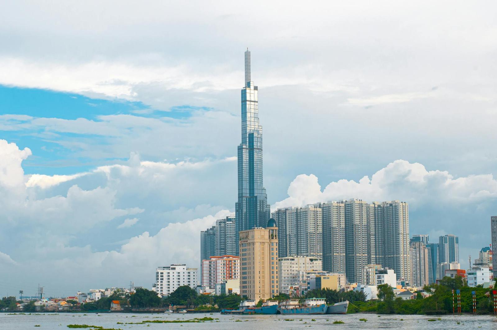 Slender skyscraper spire towering over a riverside residential skyline