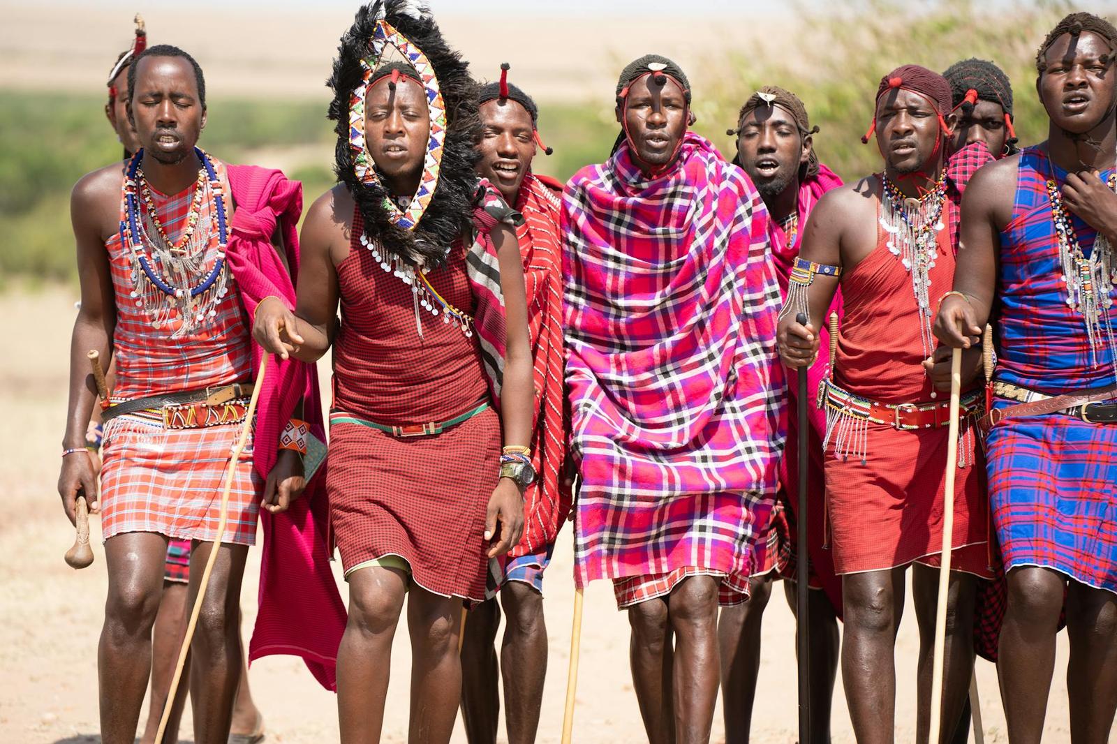 A group of Maasai people in red wraps walking together across grassland