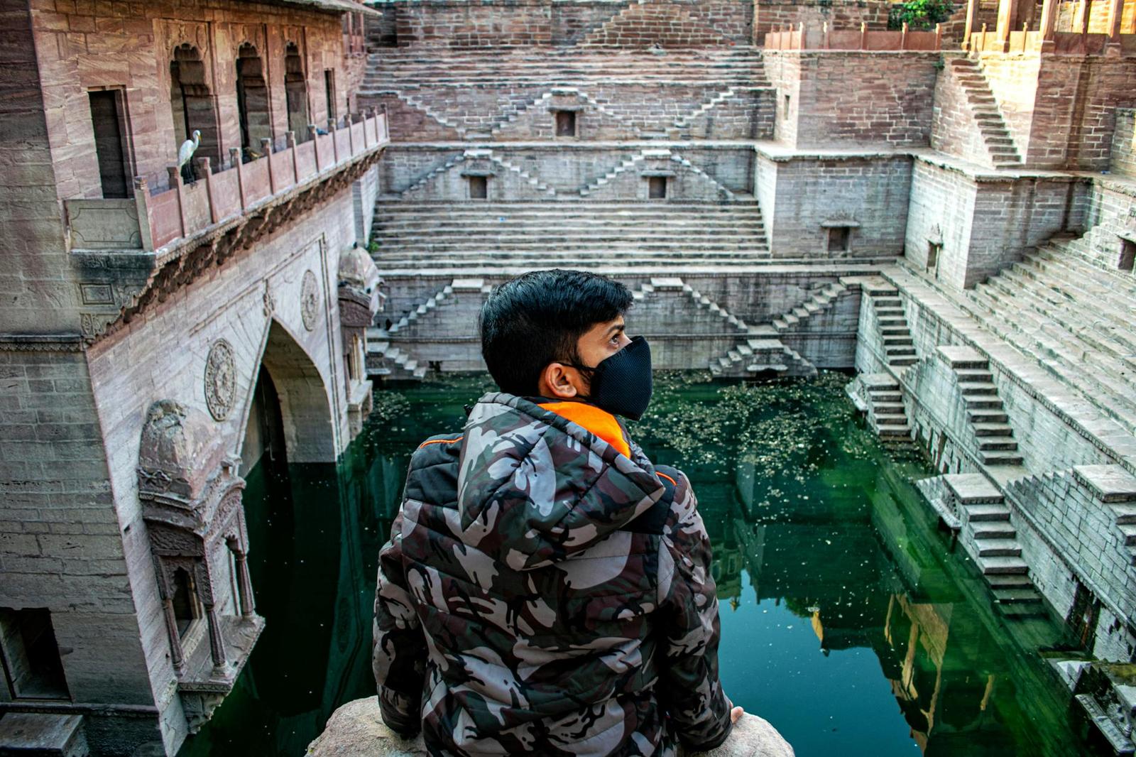 A masked man overlooks the historical Toorji Ka Jhalra stepwell in Jodhpur, India