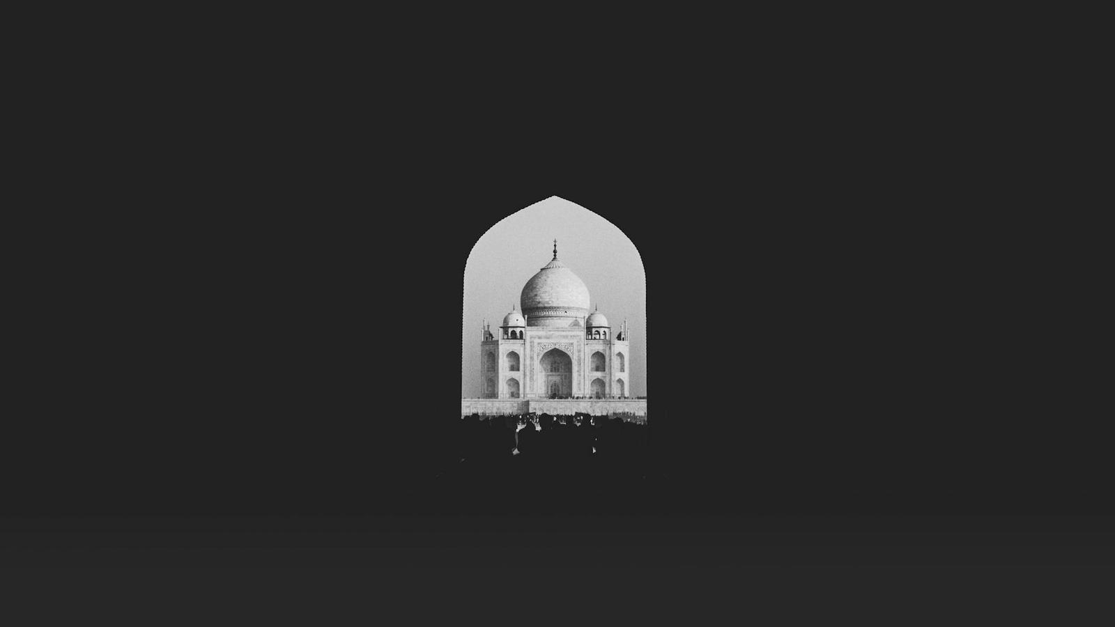 A domed marble mausoleum framed by a dark archway at night