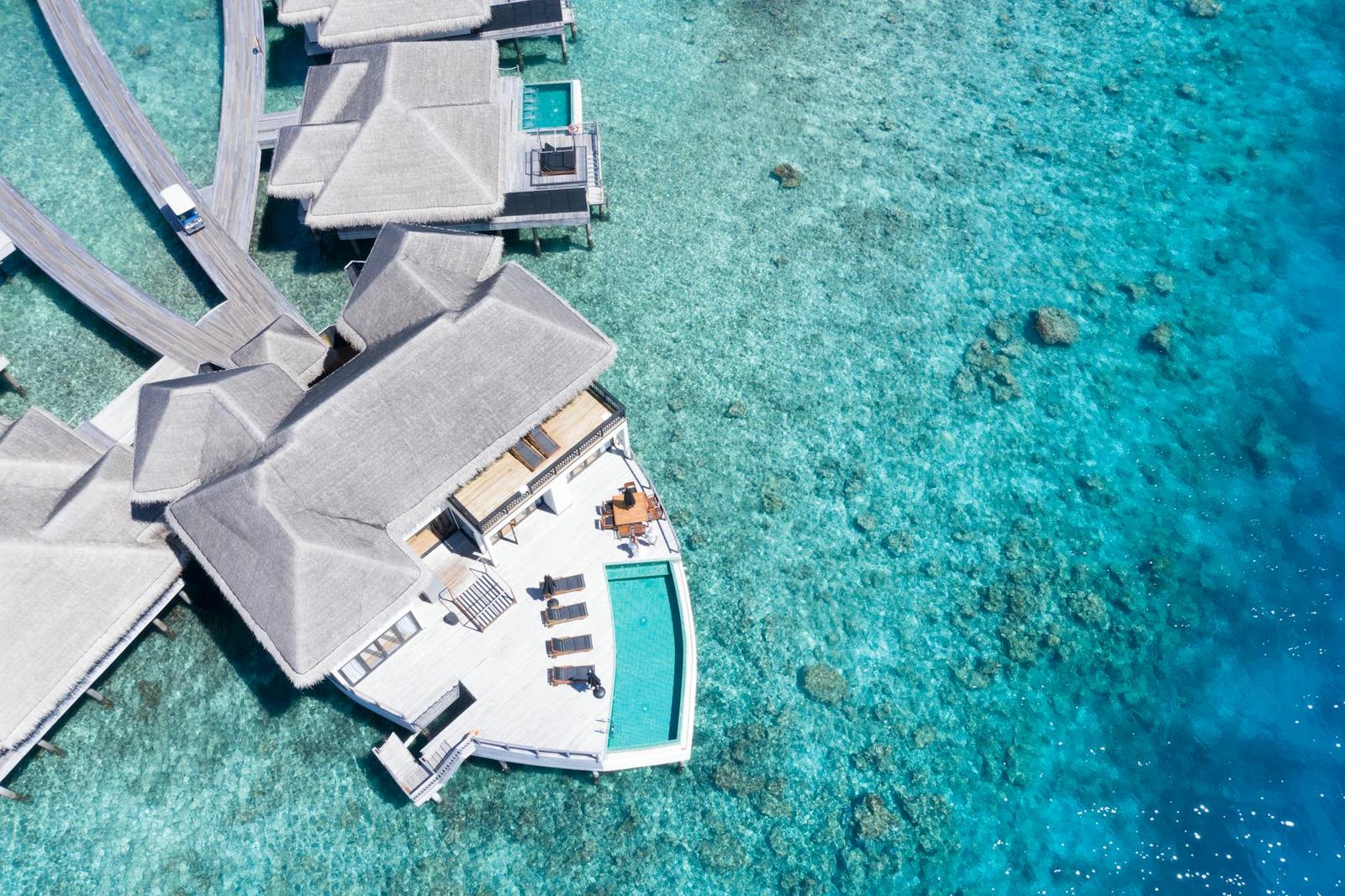 An aerial view of overwater villas with a private plunge pool over a reef