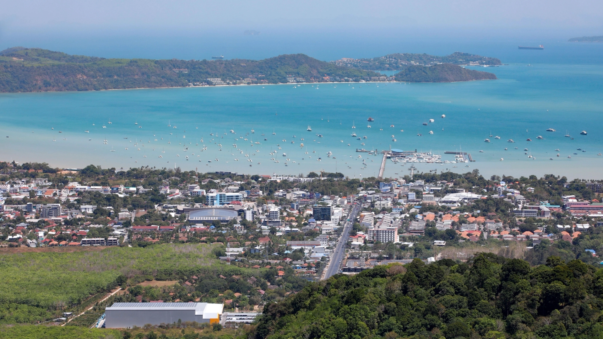 A stunning aerial view of Karon Beach, Phuket, featuring turquoise waters and urban landscape