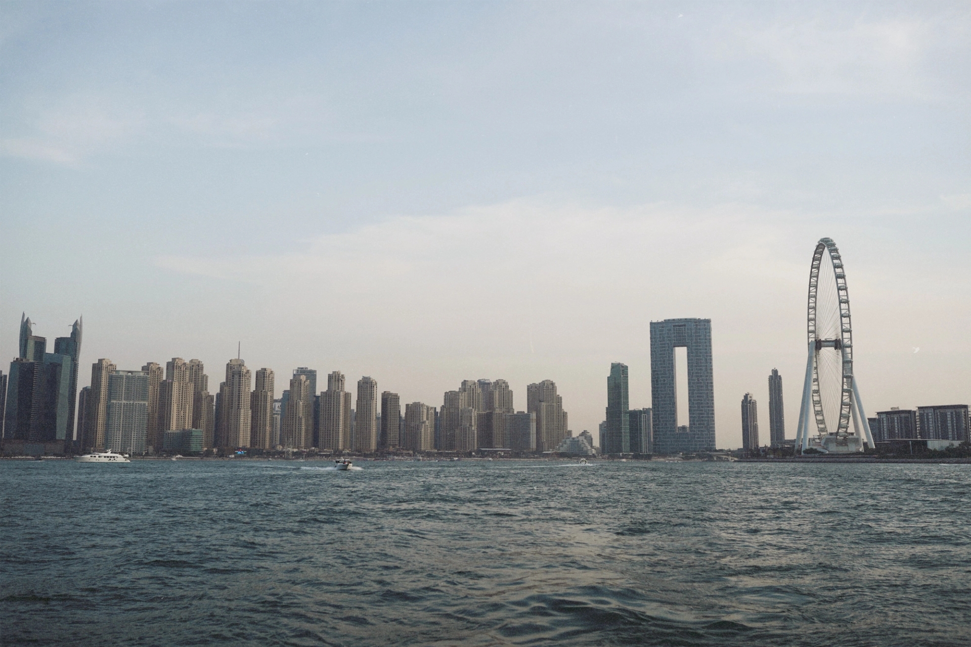 Skyline of Dubai Marina featuring modern skyscrapers and waterfront with Ferris wheel at dusk