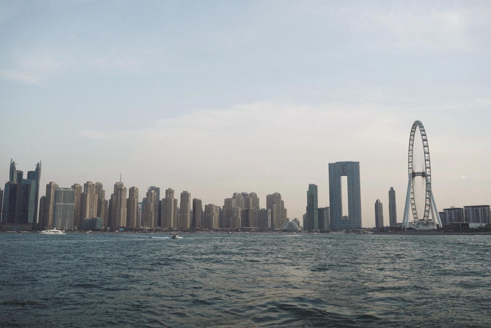 Skyline of Dubai Marina featuring modern skyscrapers and waterfront with Ferris wheel at dusk