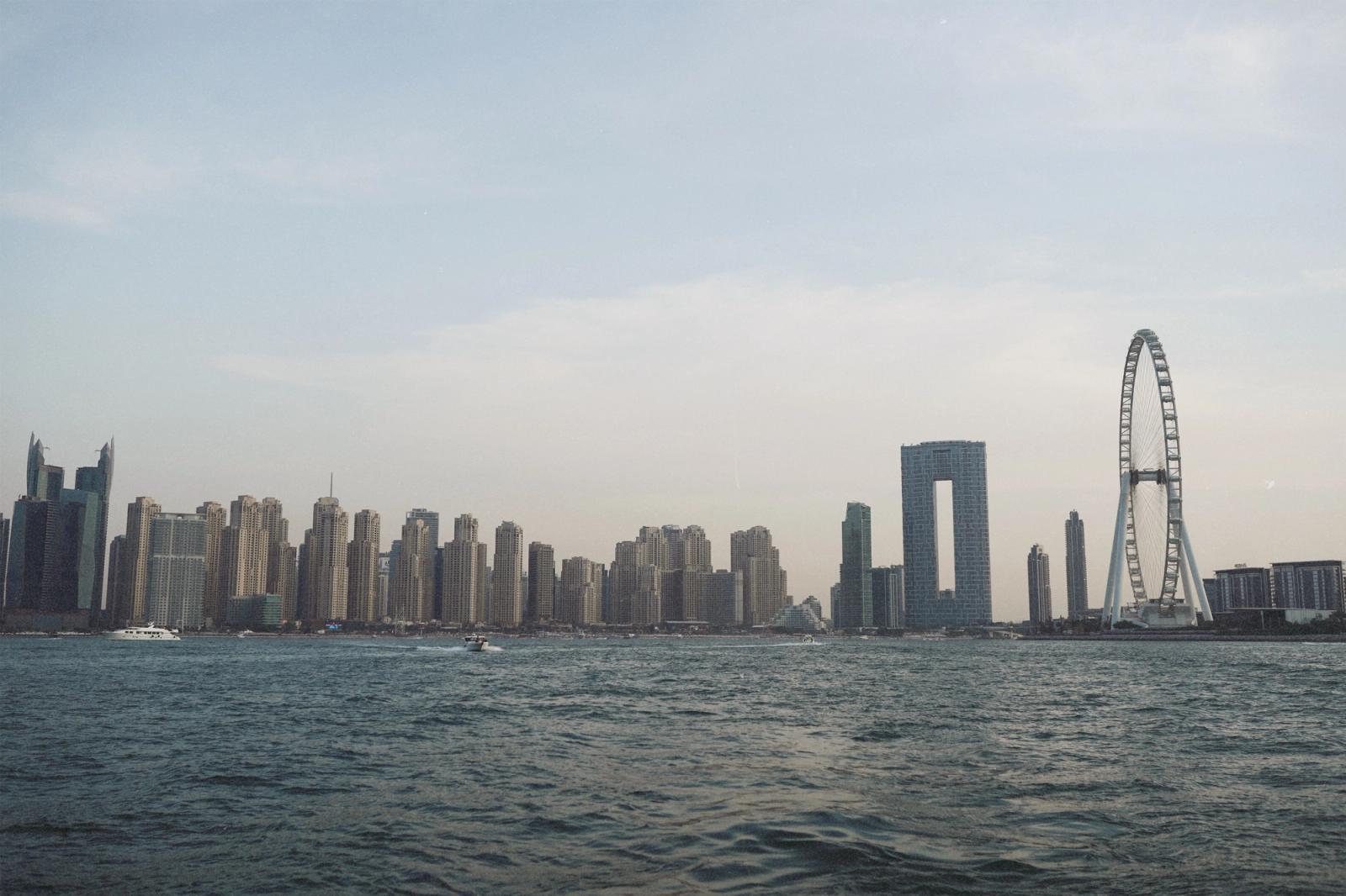 Skyline of Dubai Marina featuring modern skyscrapers and waterfront with Ferris wheel at dusk