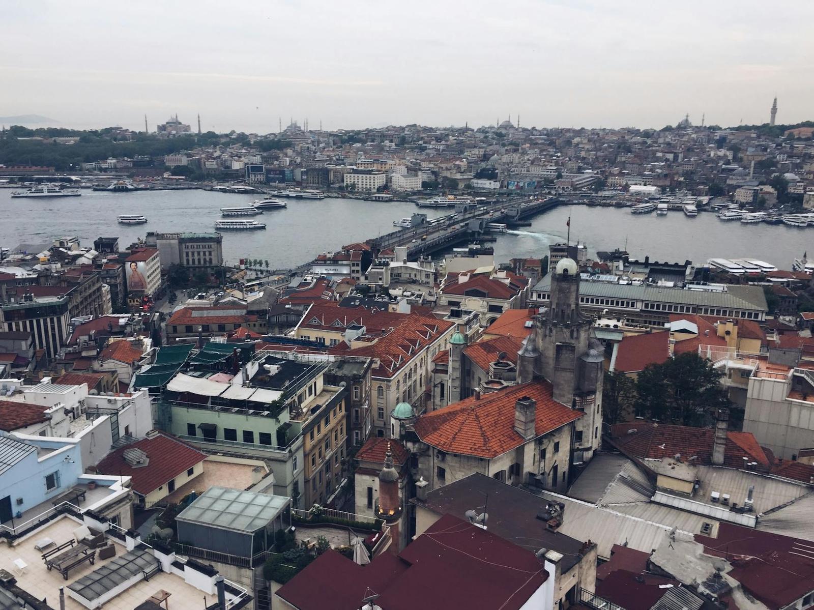 Aerial view of a historic city with red-tiled roofs beside a busy waterway