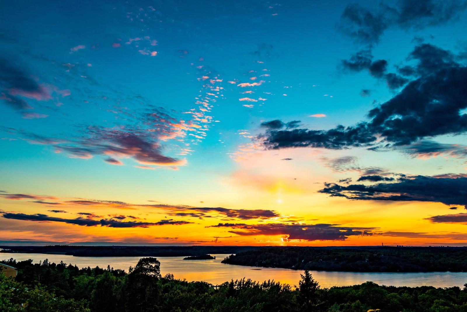 Stunning sunset over a tranquil lake in Norrmalm, Sweden. Vibrant colors and scenic reflections