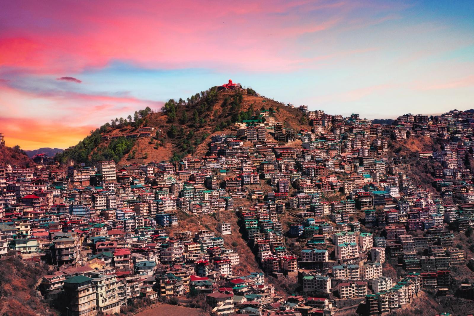 Majestic aerial view of Shimla, India with colorful buildings against a vibrant sunset sky