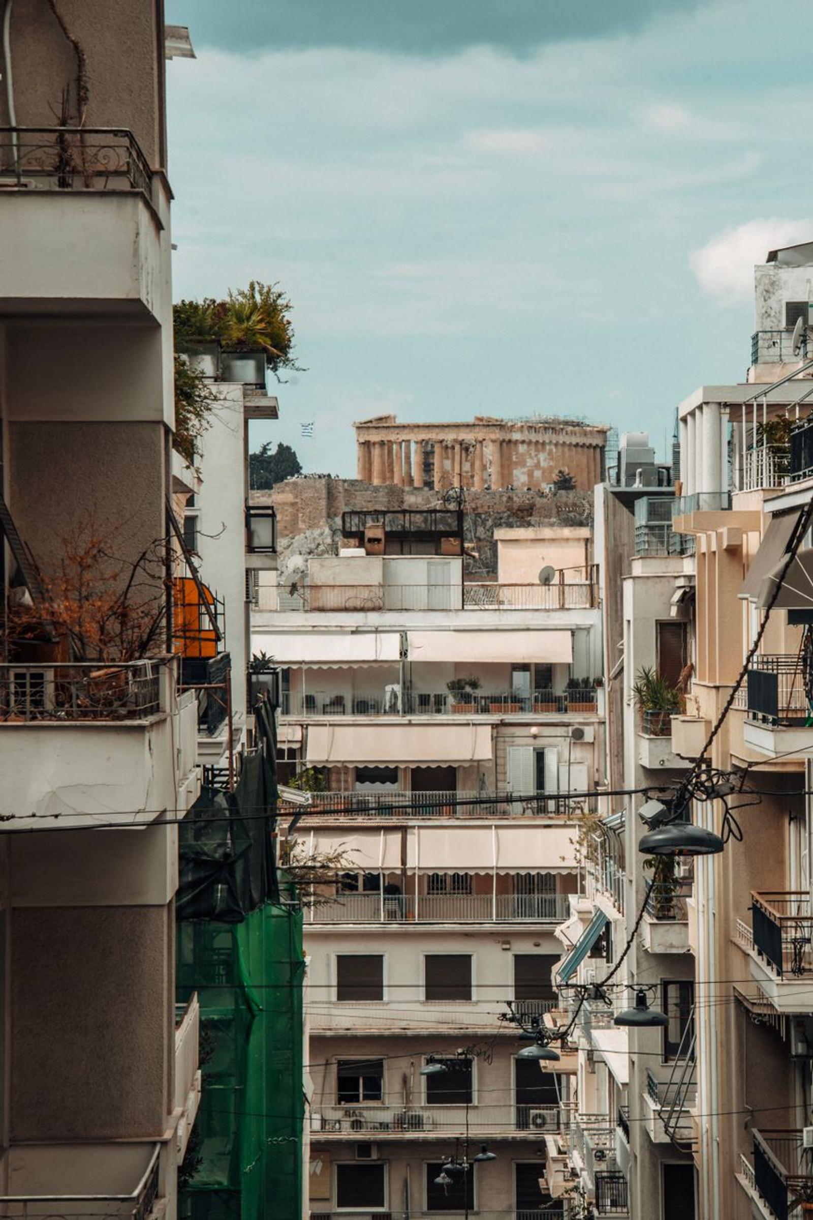 An urban street view showcasing the Parthenon amidst Athens' modern architecture