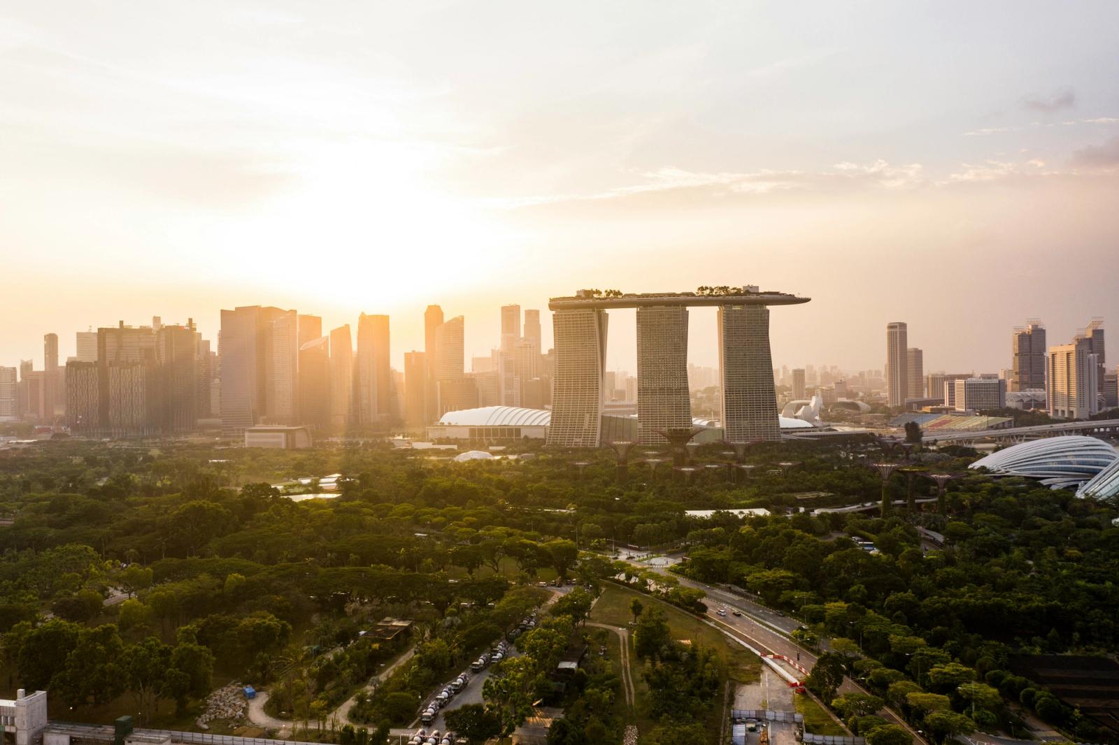 Marina Bay Sands' triple towers and rooftop deck glow at sunrise over a green park