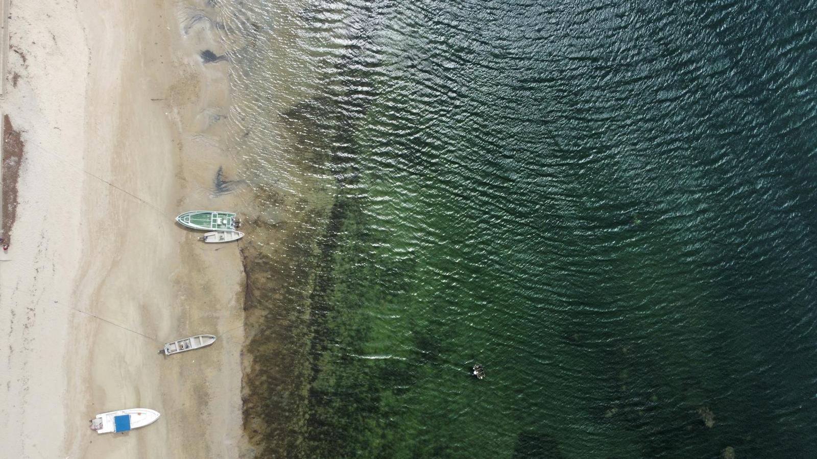 An aerial view of small boats moored along a sandy shoreline