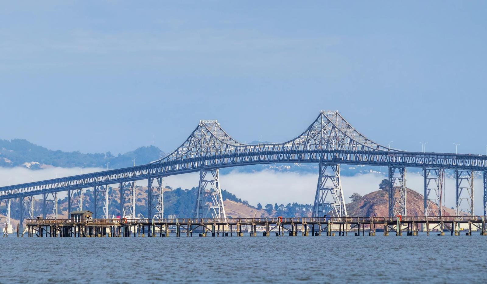 Steel truss bridge spanning the bay under a hazy sky