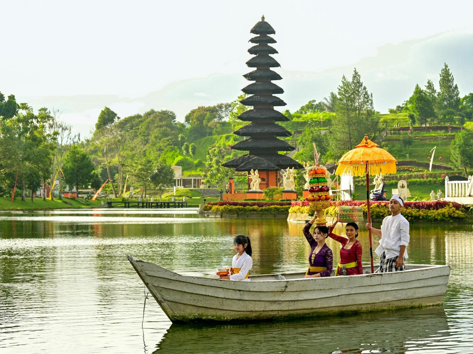 A family in traditional dress on a rowboat before a tiered black temple shrine