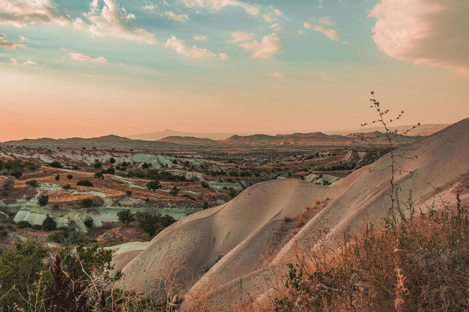 Pale eroded rock hills across a valley at sunset