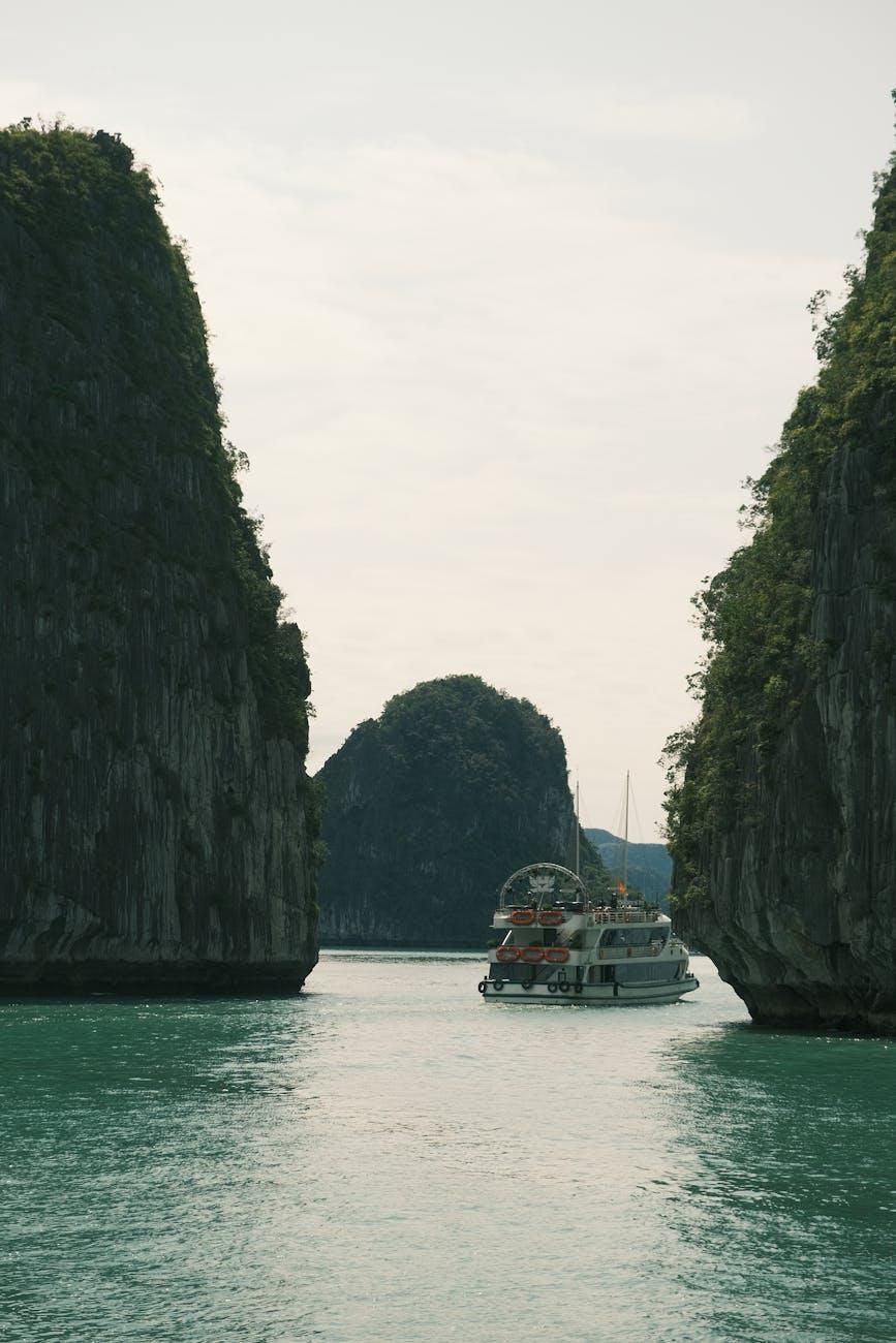Cruise boat passing between towering limestone karsts on calm water