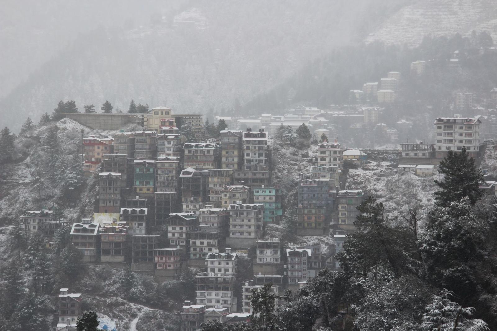Colourful hillside houses stacked on a snow-dusted slope in hazy weather