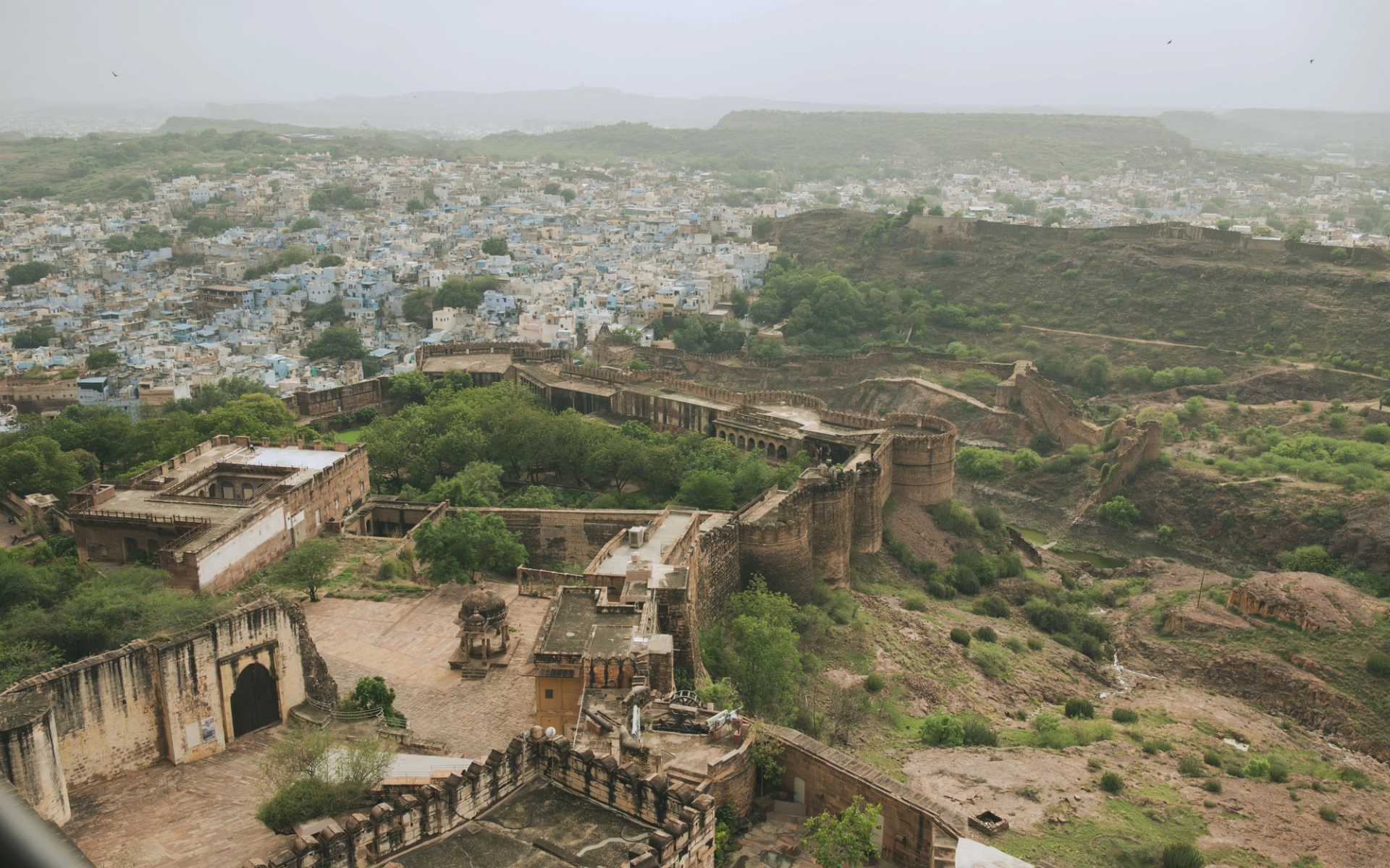 Aerial view of the historic Mehrangarh Fort overlooking Jodhpur city, framed by lush greenery