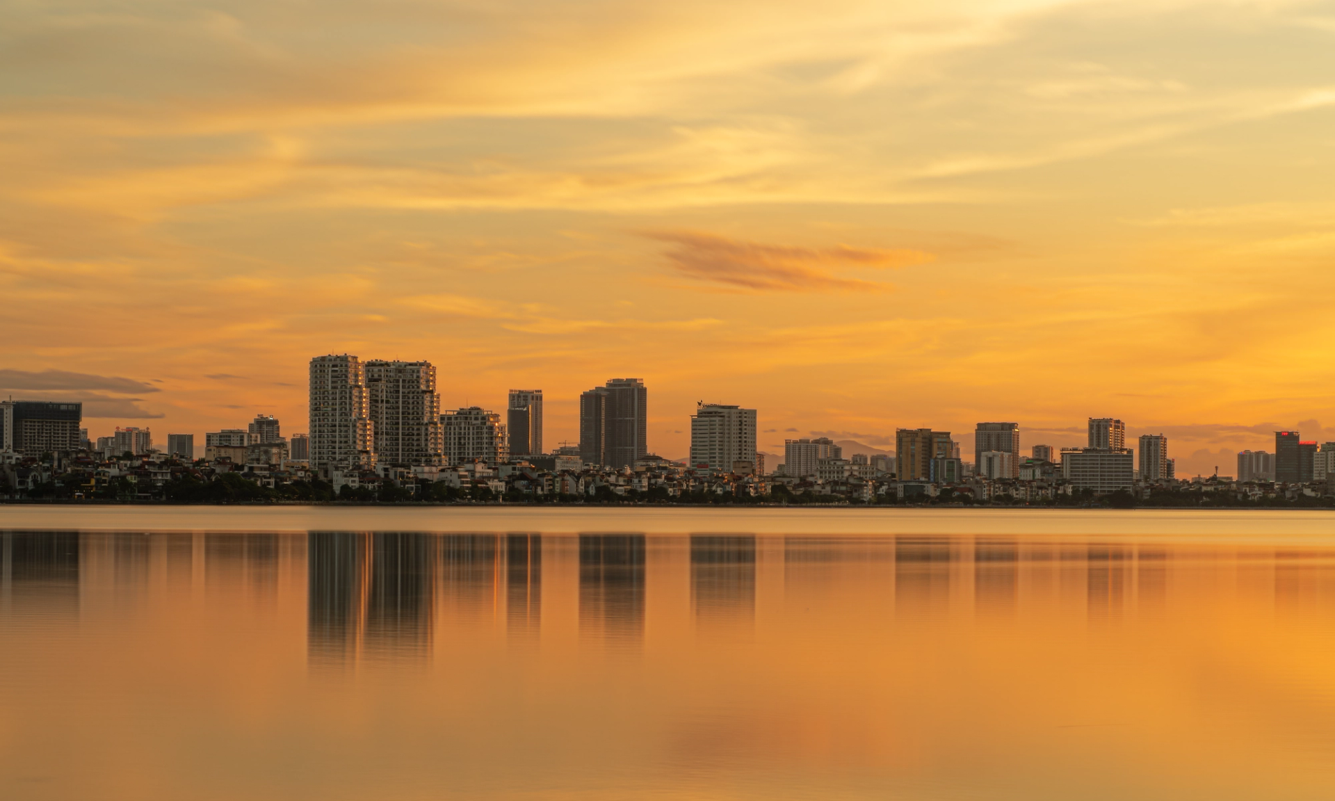 Beautiful sunset view of the Hanoi skyline reflected on West Lake, capturing urban tranquility