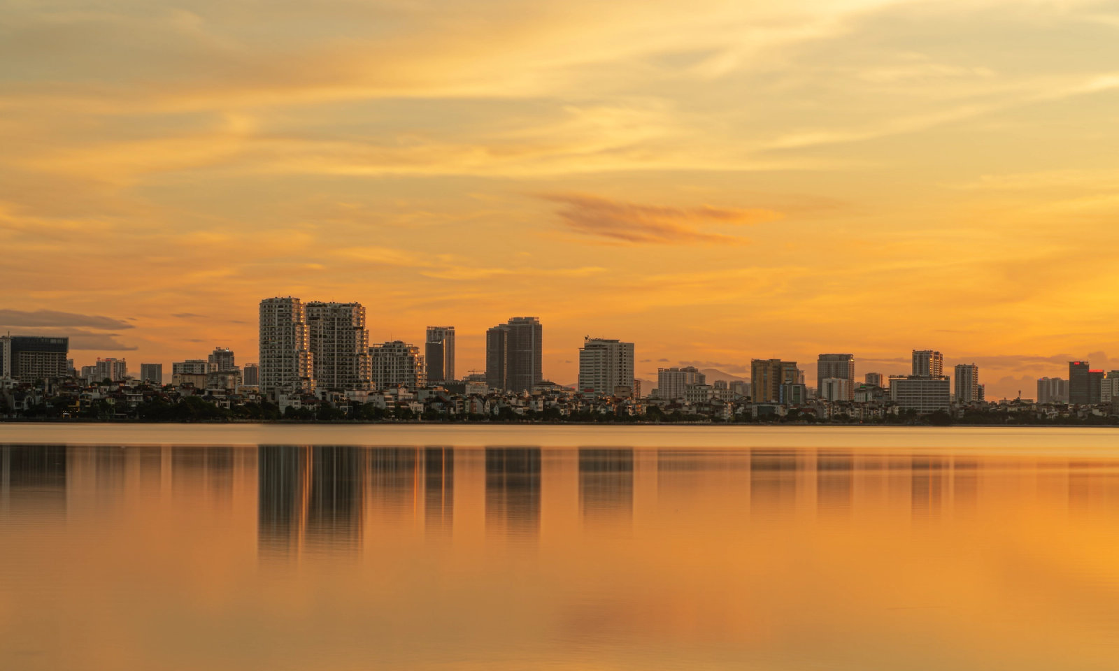 Beautiful sunset view of the Hanoi skyline reflected on West Lake, capturing urban tranquility