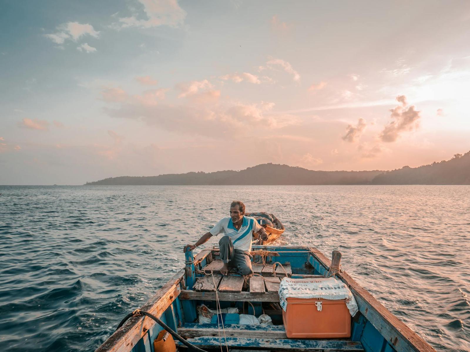 A lone fisherman navigates the calm waters of the Andaman Sea at sunrise