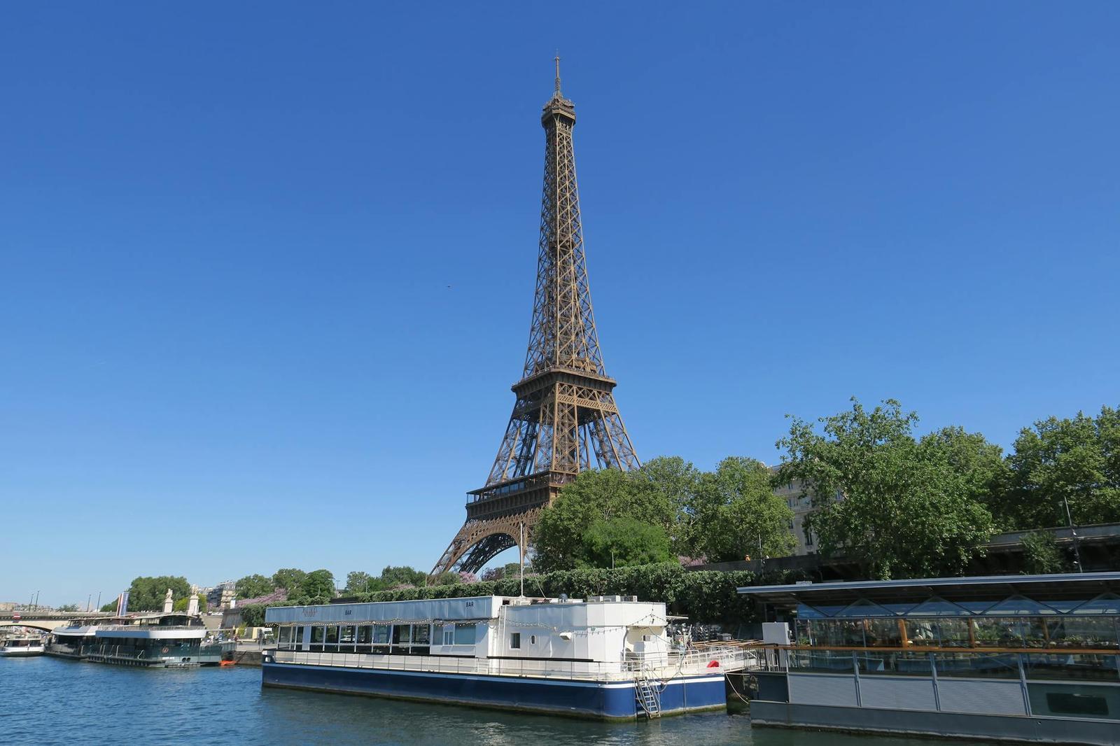 The Eiffel Tower seen from across a river with a moored boat in the foreground
