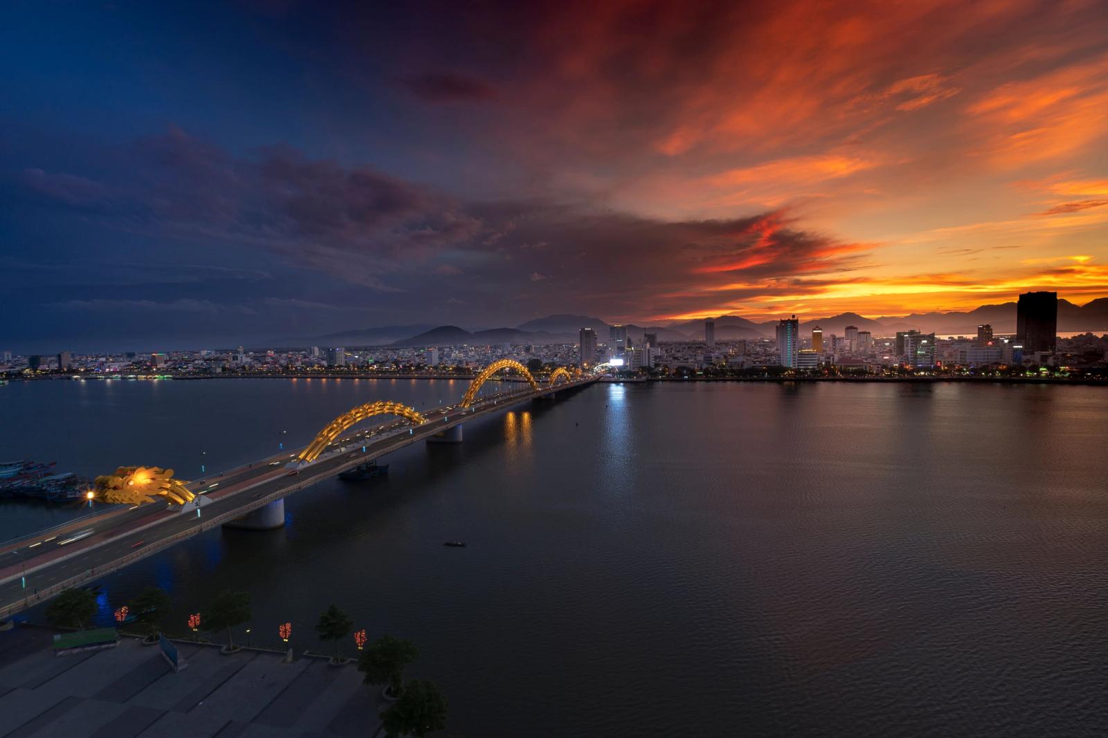 Beautiful sunset over the illuminated Dragon Bridge in Da Nang, Vietnam, highlighting the vibrant cityscape