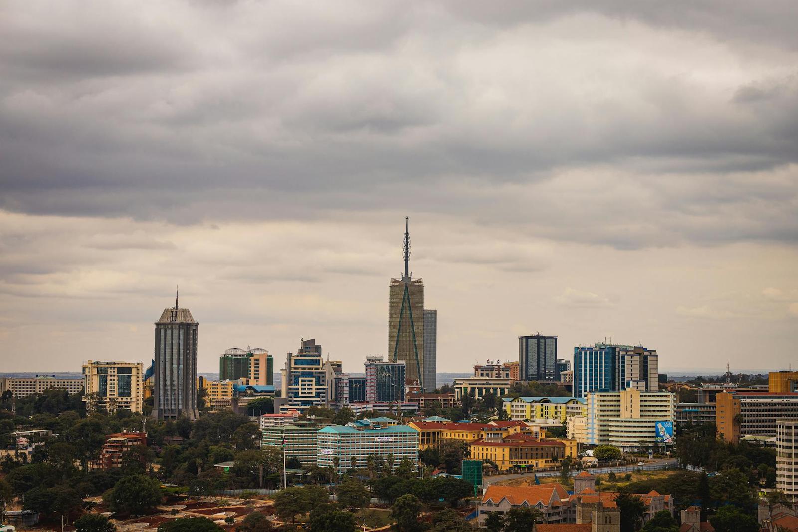 A city skyline of high-rise towers under a heavy cloudy sky