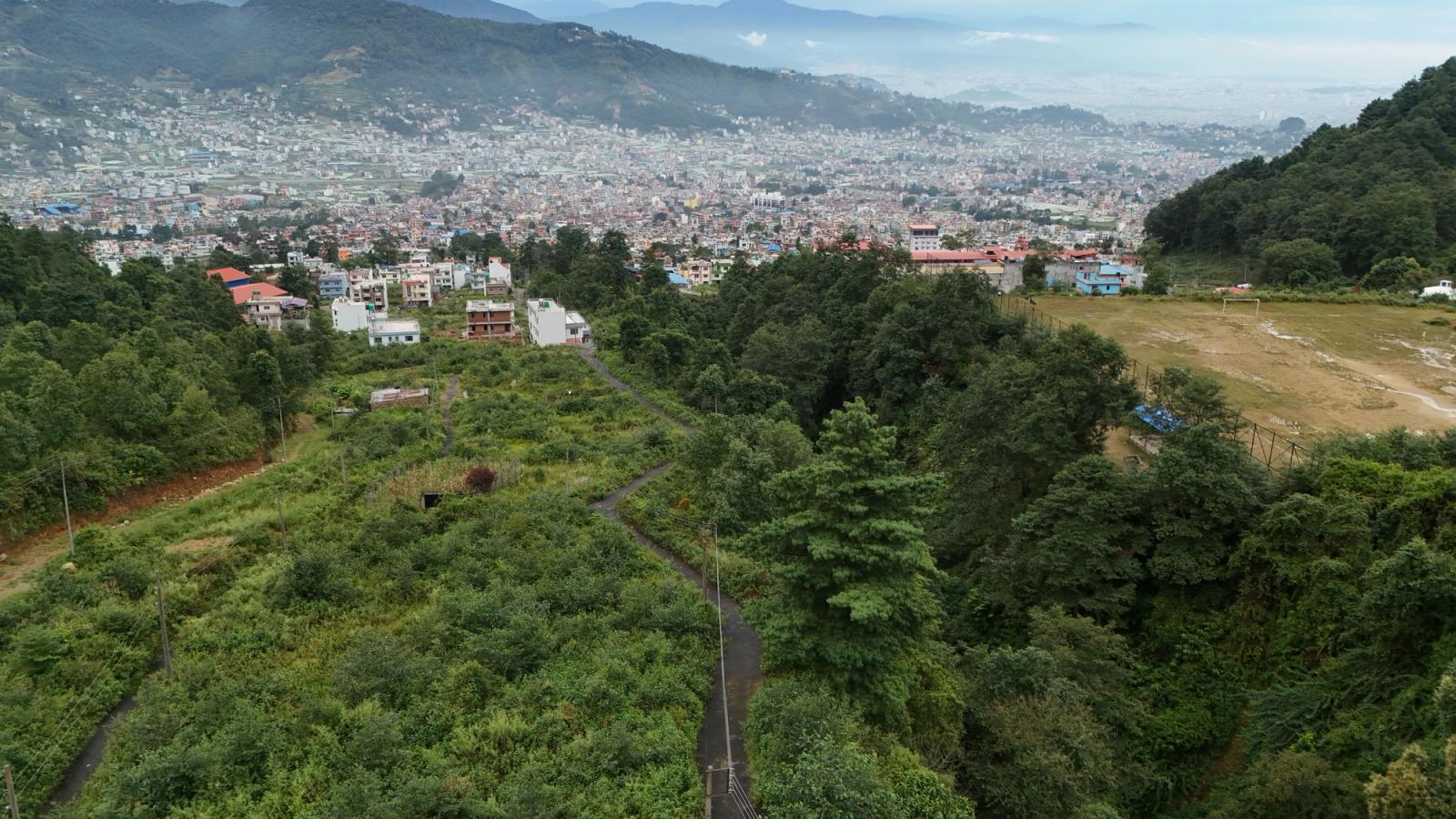 Aerial view of lush greenery leading to the bustling Kathmandu Valley cityscape