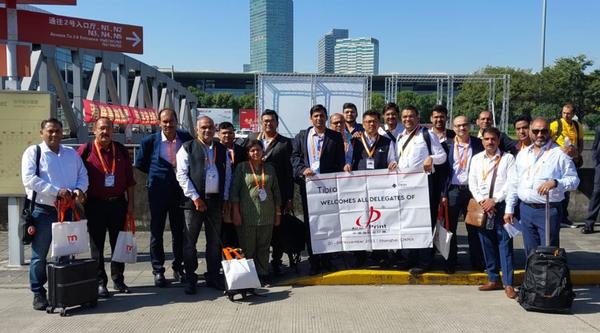 Group of delegates posing outdoors with a banner