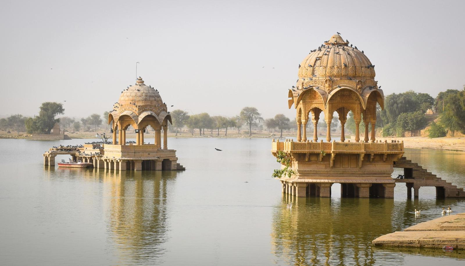 brown concrete building near body of water during daytime Cenotaph on Gadsisar lake in Jaisalmer, Rajasthan (India)