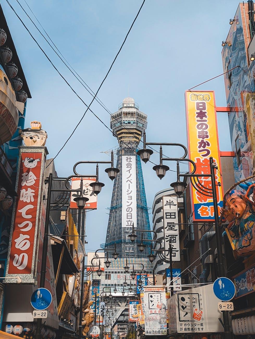Observation tower rising above a narrow street lined with vibrant signboards