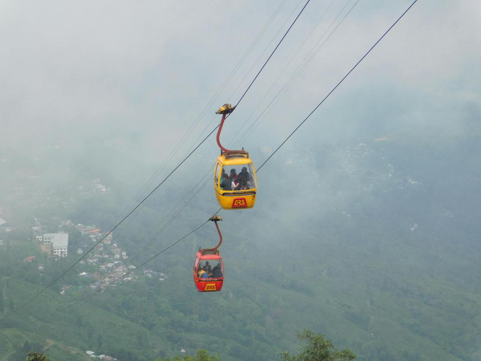 Two colorful cable cars suspended over misty mountains in Darjeeling, India