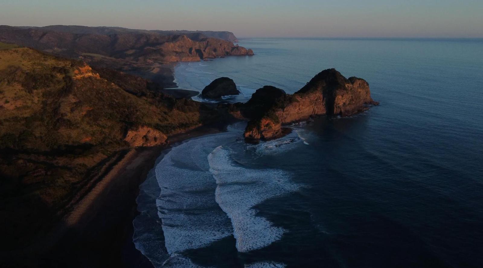 Aerial view of a dark cove and rocky headland at twilight