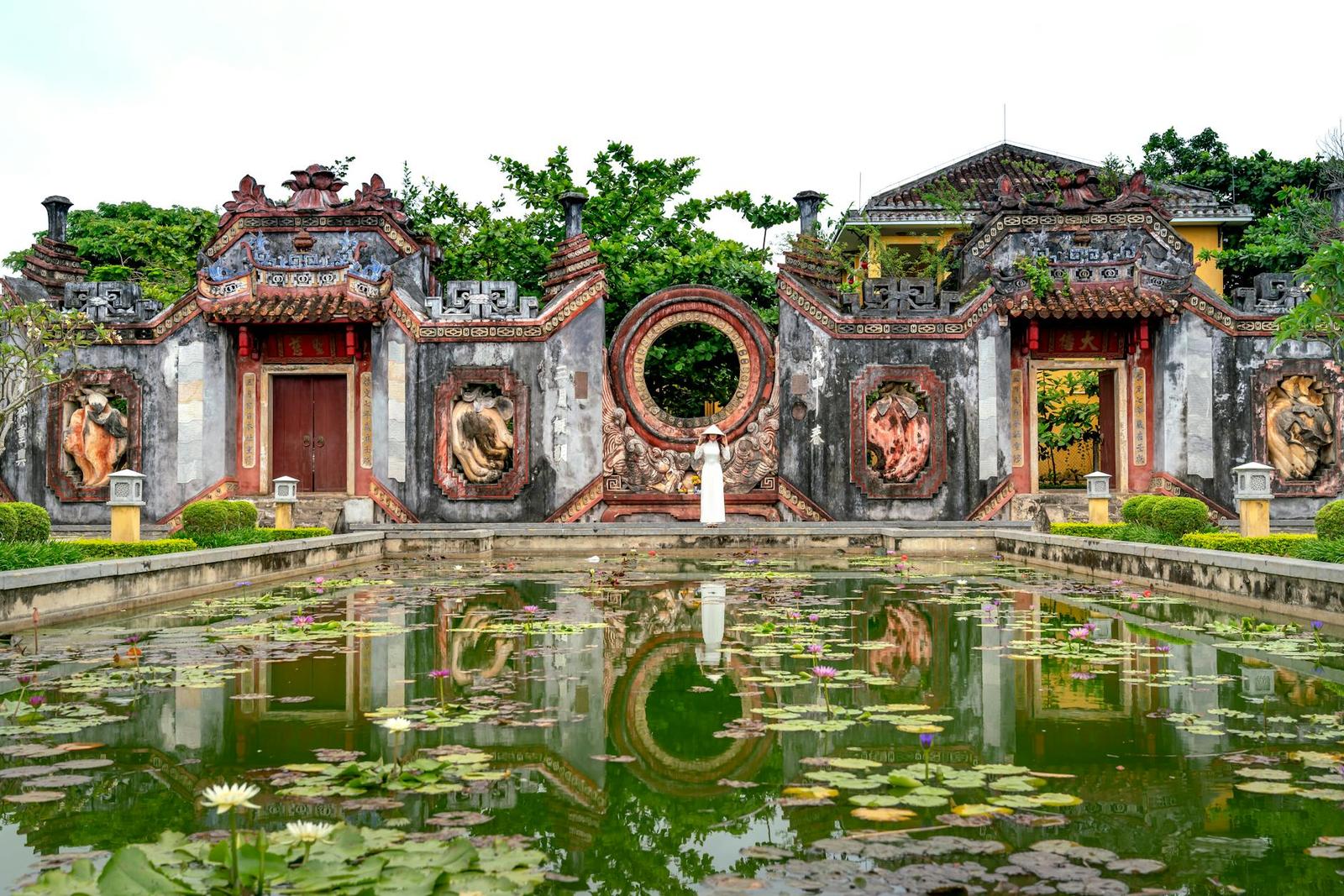 Scenic view of a historic temple facade with a tranquil pond and lotus flowers