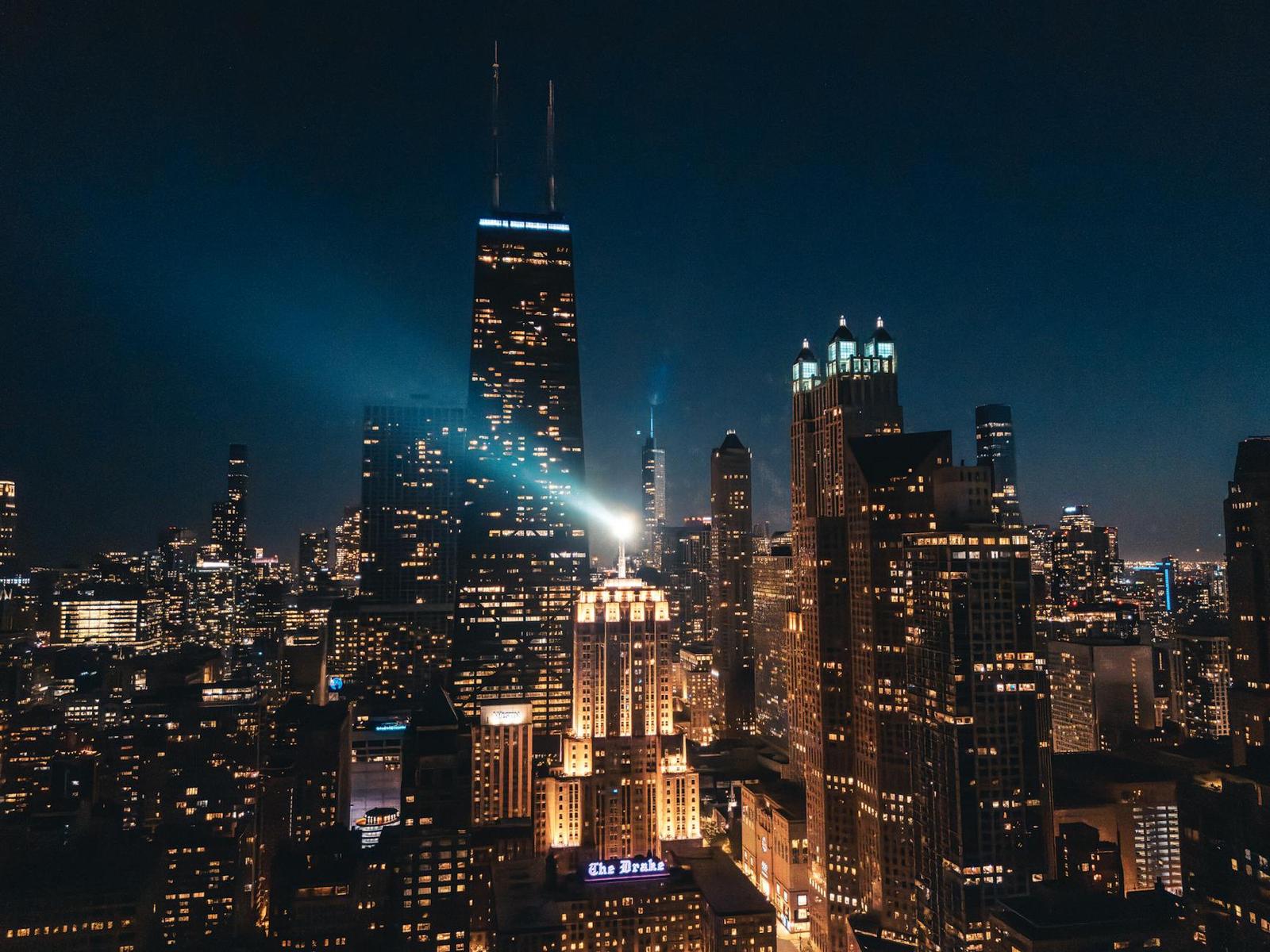 A lit-up city skyline of skyscrapers glowing against the night sky