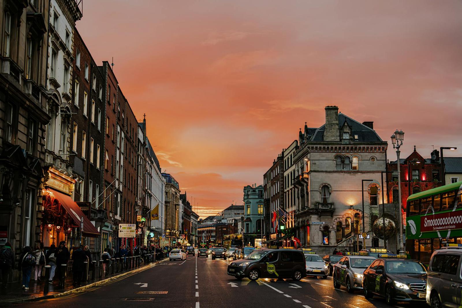 A busy city street glowing under a pink sunset sky