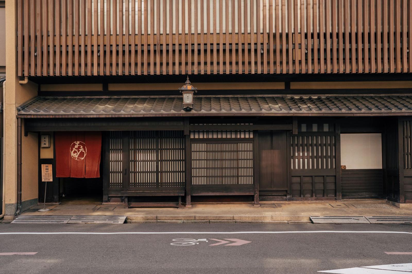 A traditional wooden machiya house facade with sliding screens and a curtain