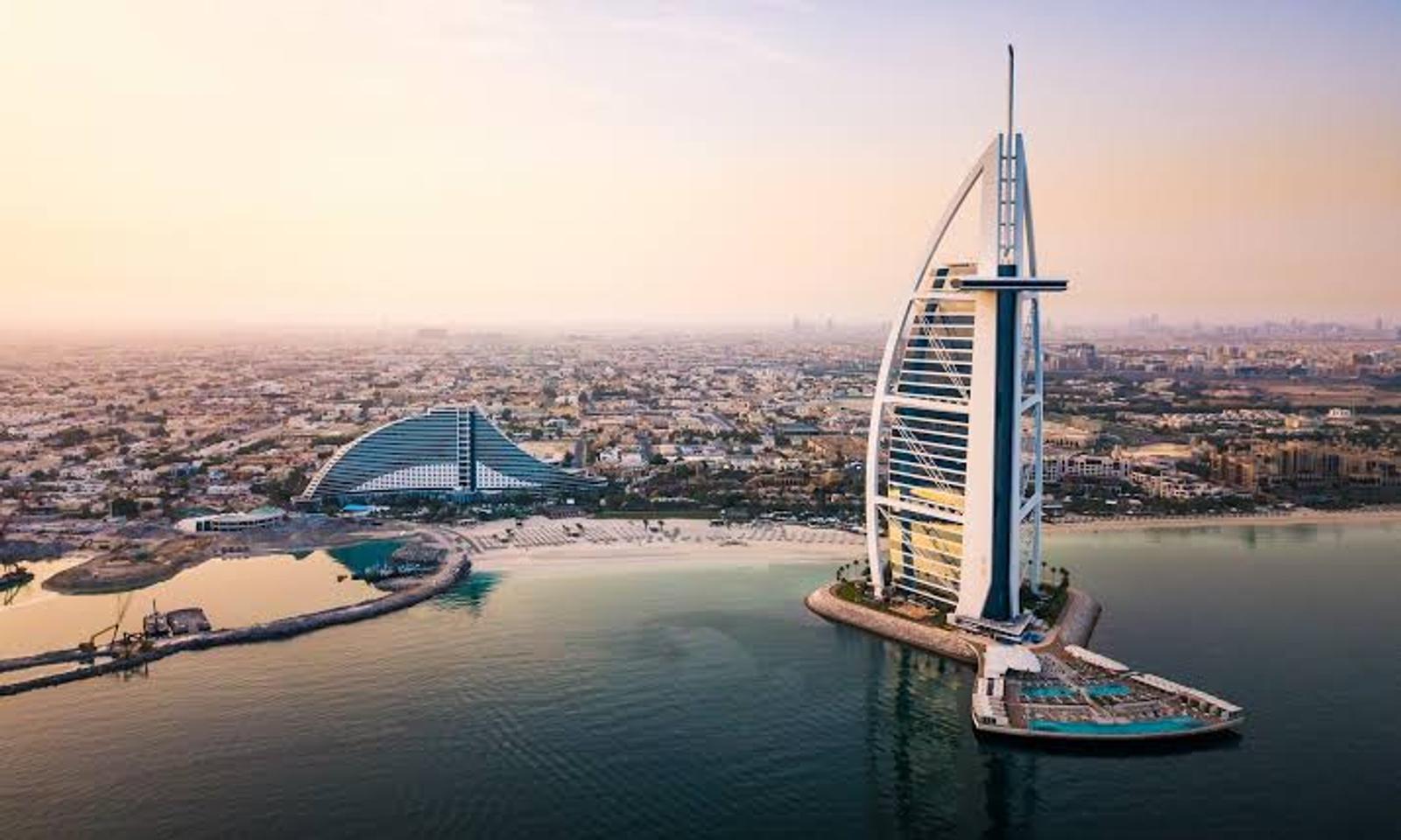 Burj Khalifa silhouetted above the Dubai skyline at sunset over water