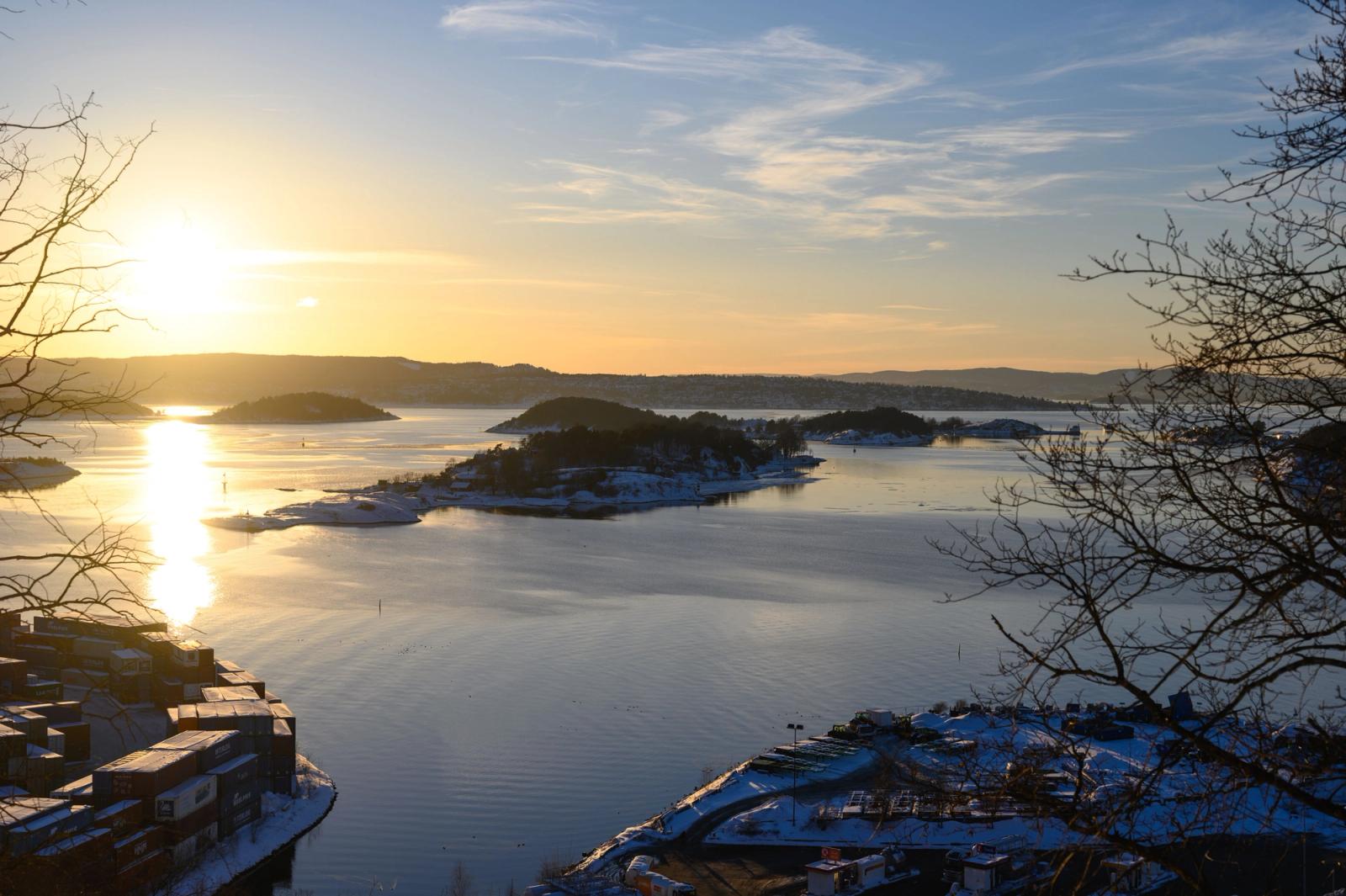 A beautiful winter sunset over Oslo Fjord, highlighting islands and a calm sea with silhouetted trees