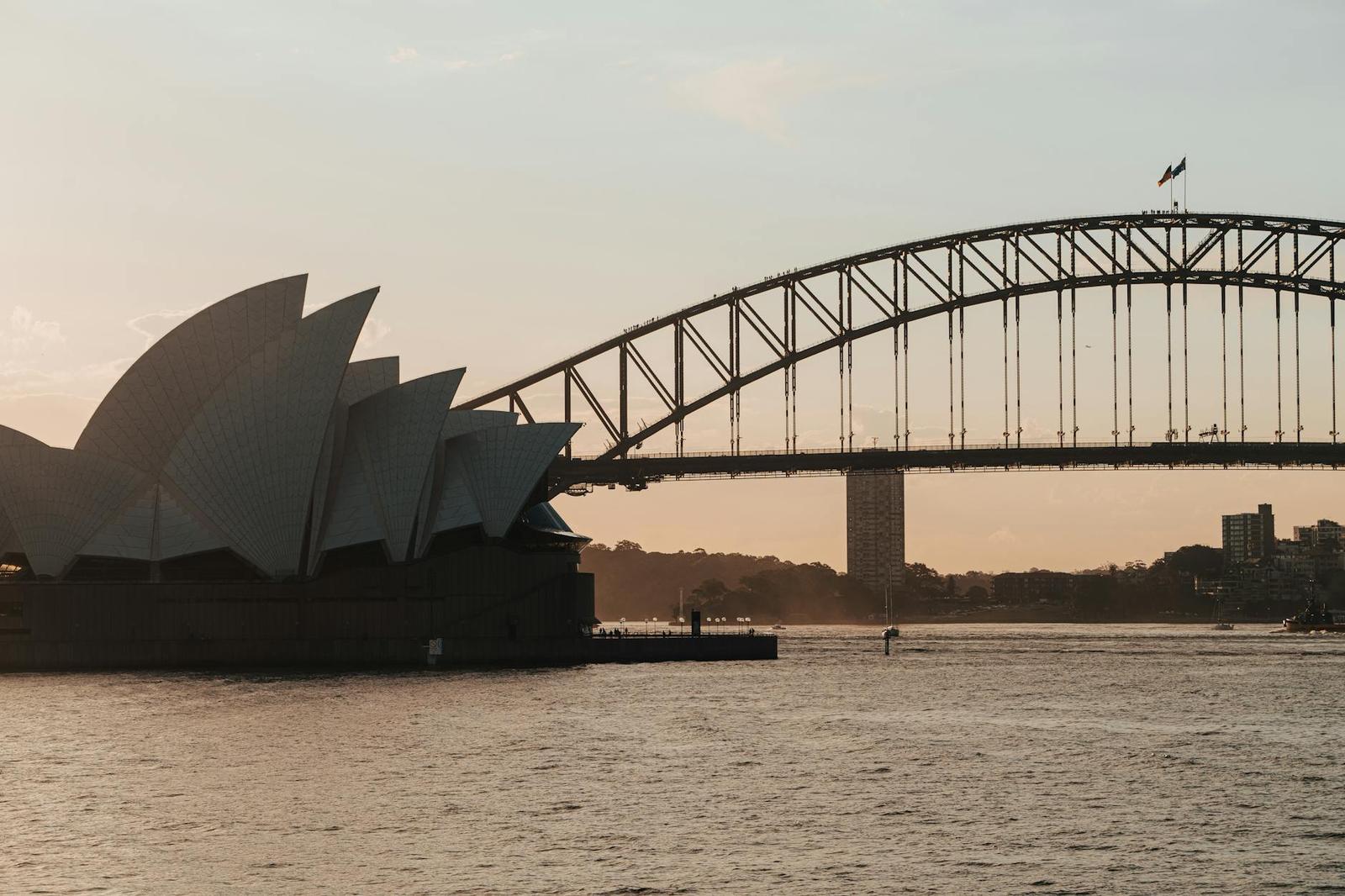 A scenic view of Sydney Opera House and Harbour Bridge at dusk, captured on a tranquil evening