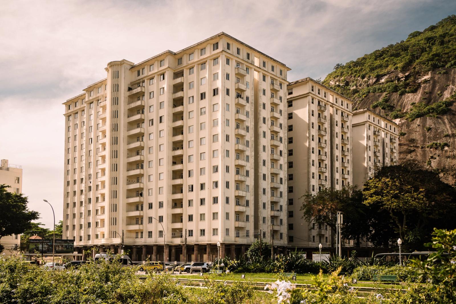 A contemporary residential building in Rio de Janeiro with a scenic mountain backdrop and clear skies