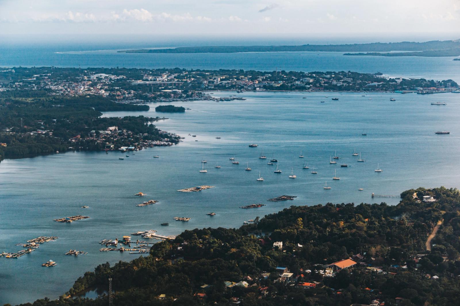 Stunning aerial view of a coastal city with sailboats dotting the bay, displaying vibrant scenery and serene waters