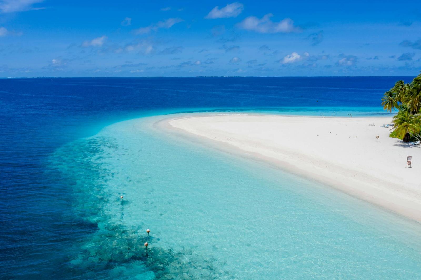 Aerial view of a curving sandbank meeting deep blue water