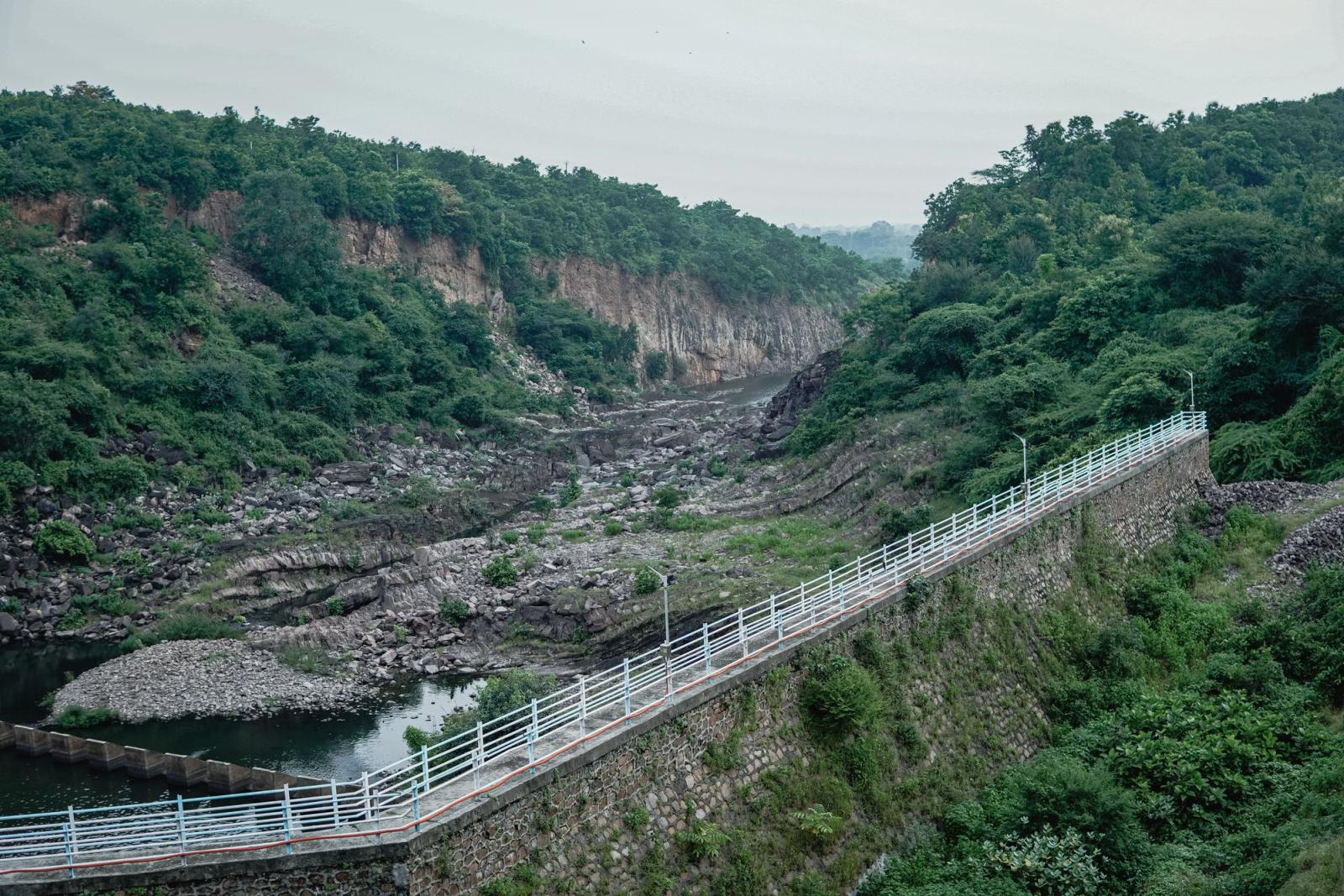Beautiful landscape of a river gorge surrounded by lush greenery and a stone wall in GJ, India