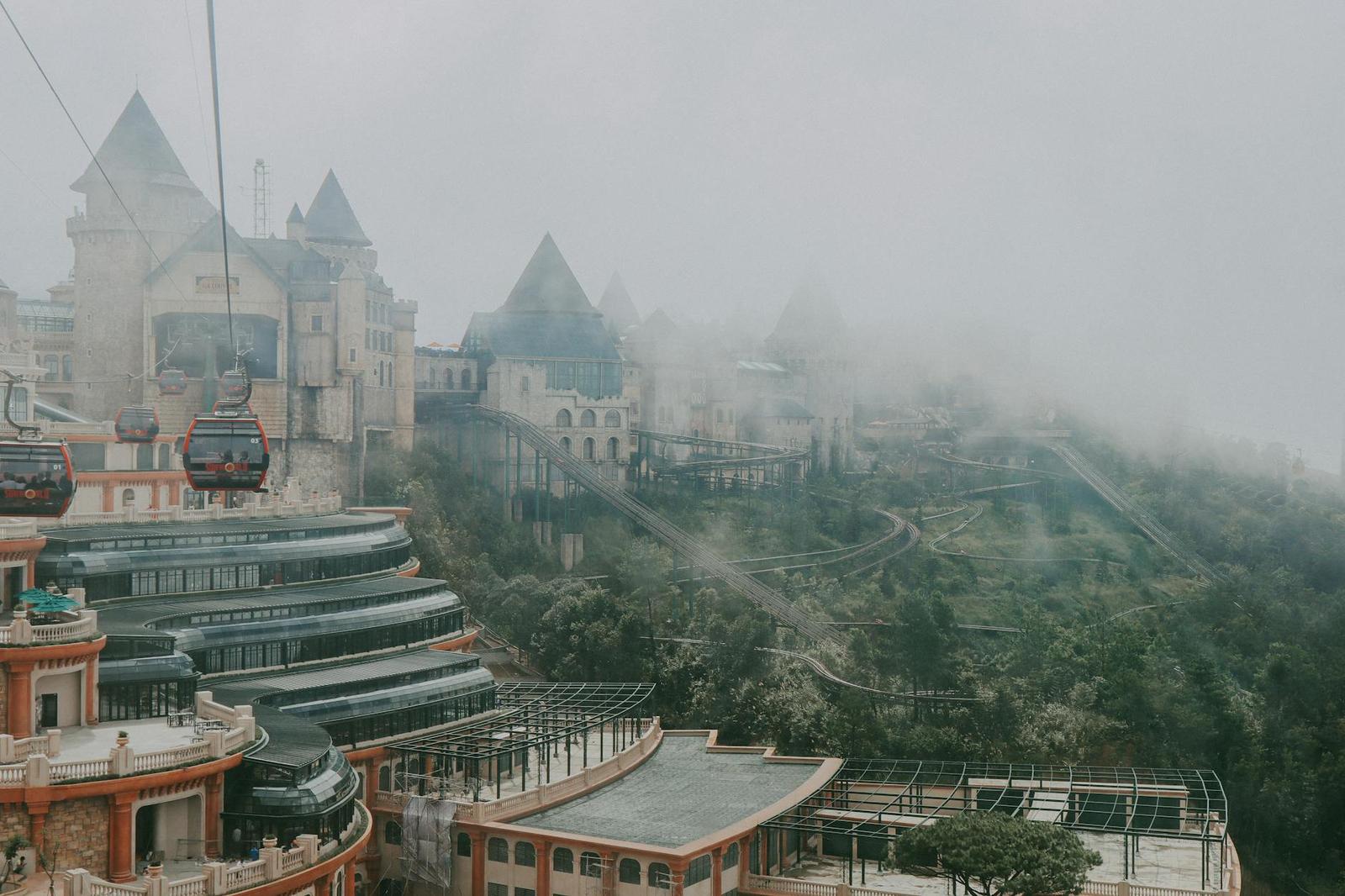 Cable cars gliding above turreted resort buildings shrouded in thick mountain fog