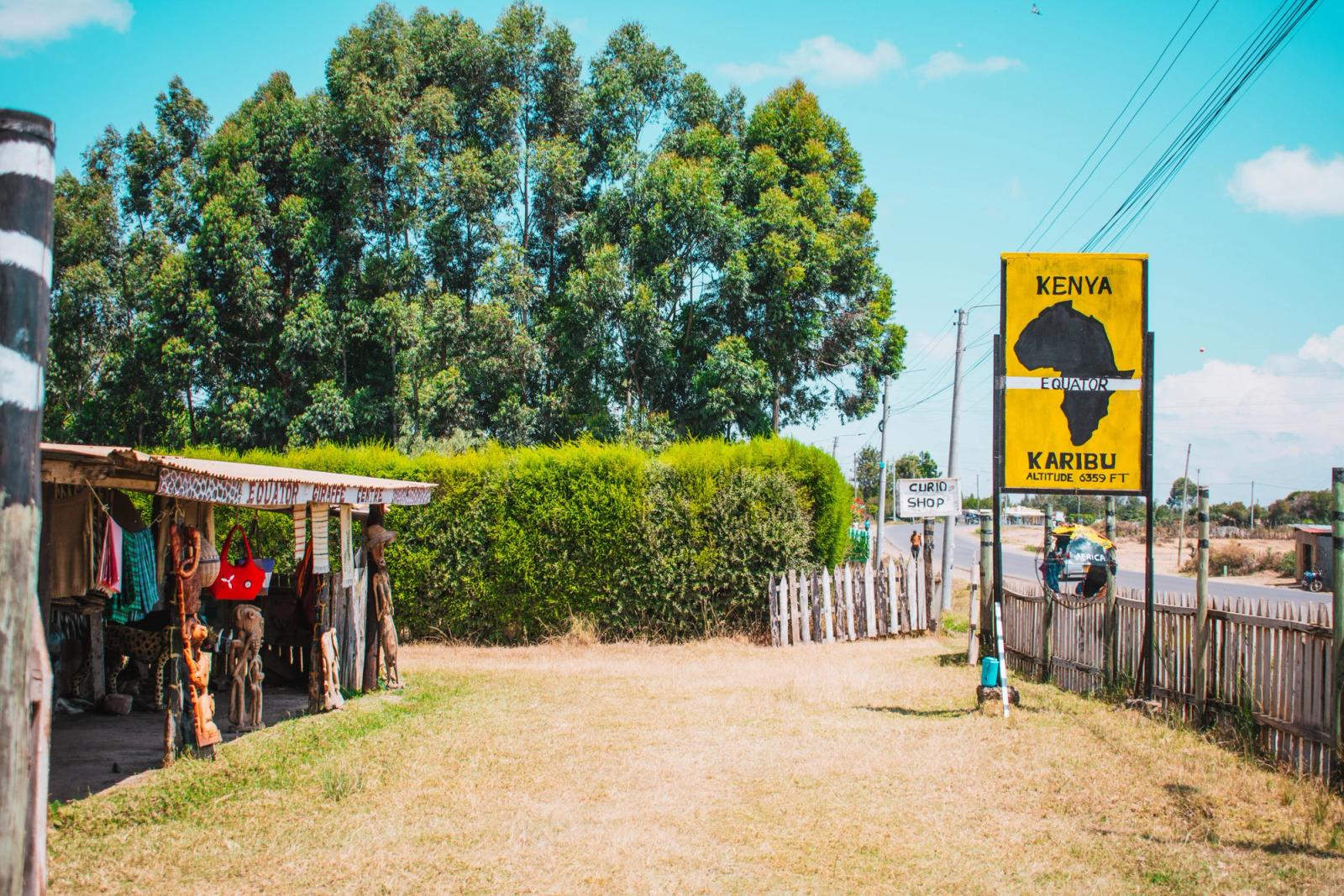 Scenic view of equator landmark sign at Nanyuki, Kenya, with local craft shop and lush greenery