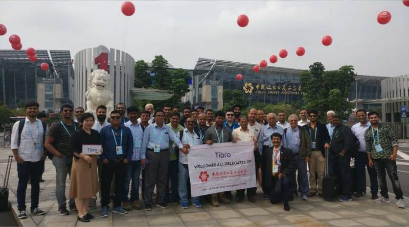 A group of people posing in front of a historic monument holding a banner.